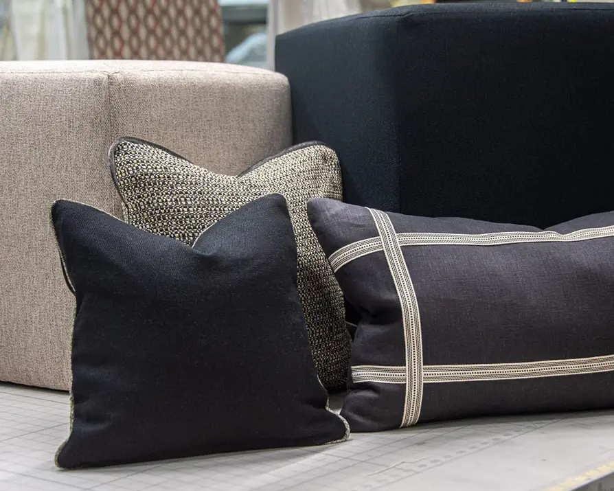 Black and tweed pillows on a sofa, one with a ribbon trim