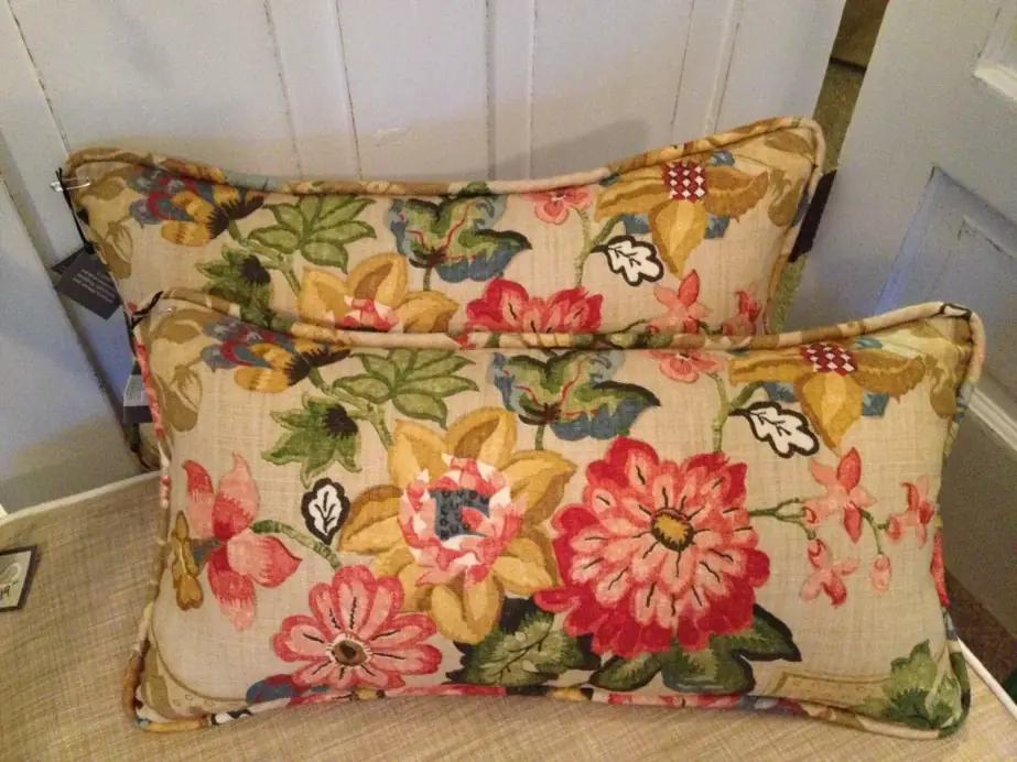 Two floral lumbar pillows with contrast piping on a cream sofa