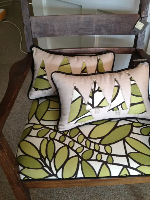 Pillows with appliqued trees on a leaf-print bench