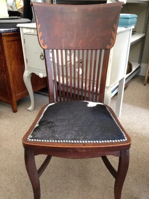 Dark wood spindle-back chair with a cowhide seat